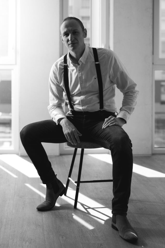 Photo portrait professionnelle d'un photographe de Reims et assis sur un tabouret.