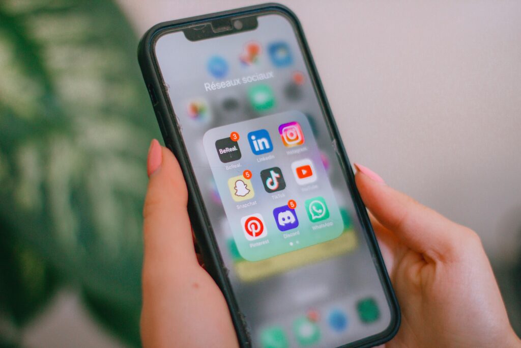 Téléphone qui affiche tous les réseaux sociaux gérés par une agence de communication digitale à Reims